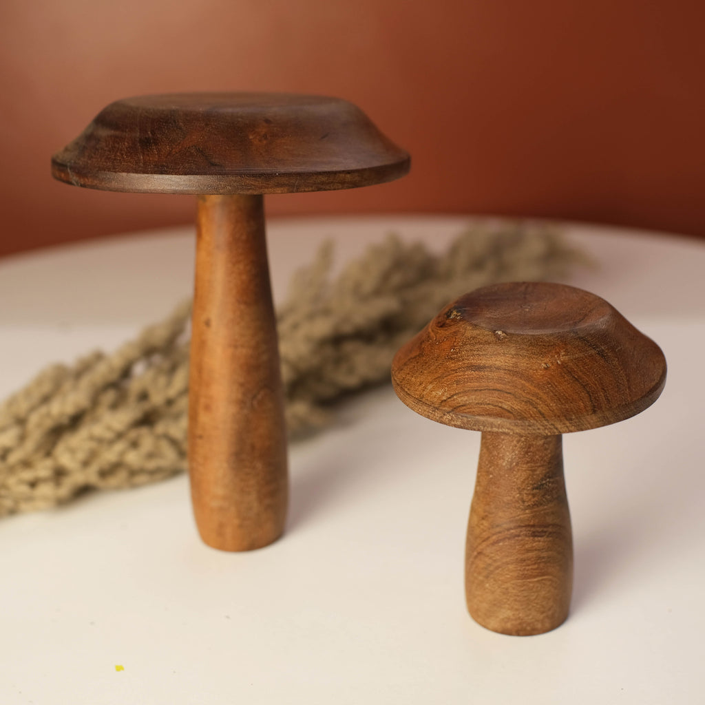 A pair of natural wooden mushrooms placed on a tabletop, evoking rustic charm.