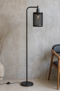 Black floor lamp against a textured wall with a chair and vase in the background.