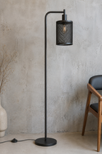 Black floor lamp against a textured wall with a chair and vase in the background.