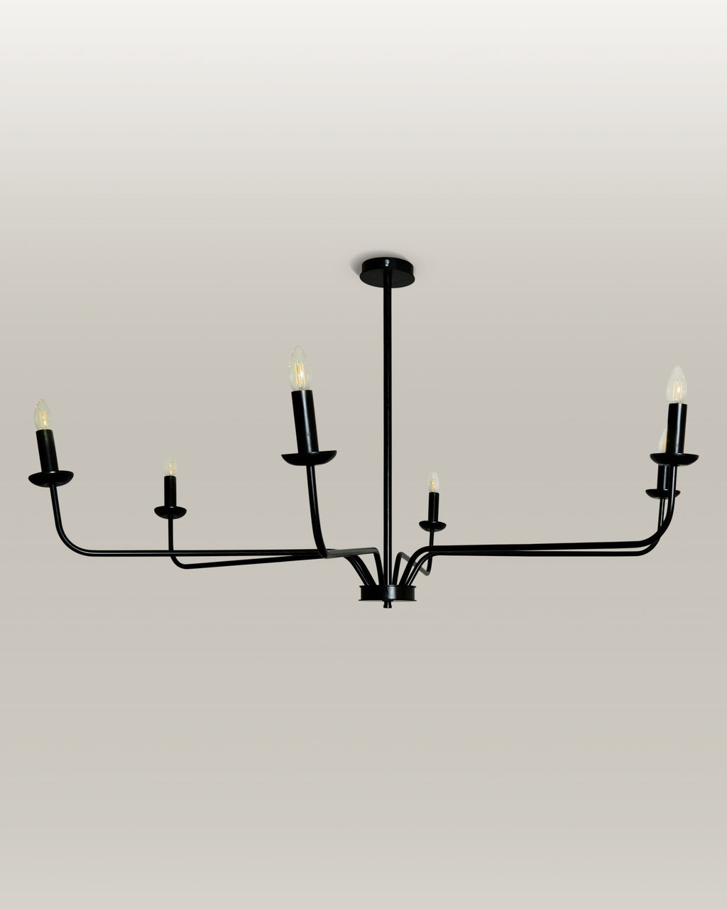 Candlelight Elegance Chandelier with sleek black metal arms and candle flame light bulbs, hanging in a modern living room.