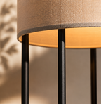 Close-up of a lamp with a brown shade and black metal base against a blurred background