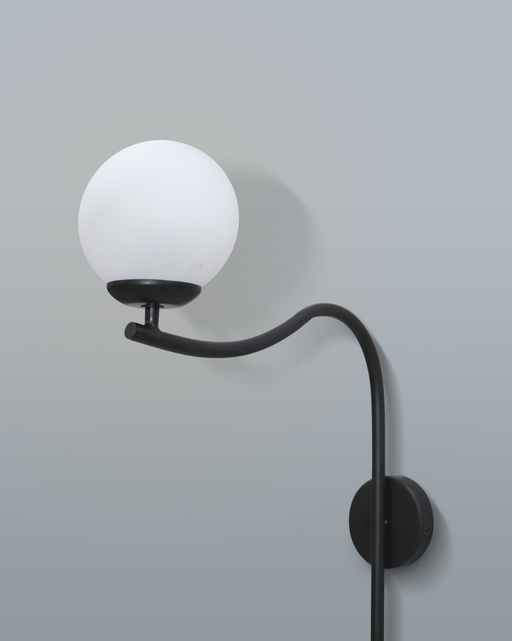 Contemporary arched wall lamp with a sleek black design and a soft-diffused white lampshade, mounted in a living room