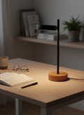 Desk lamp on a wooden desk with books, glasses, and a pen in a home office setting.