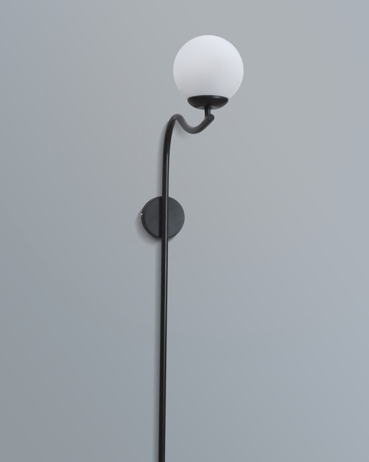 Elegant arched wall lamp featuring a black metal frame and a soft-glow white lampshade, enhancing a stylish interior.
