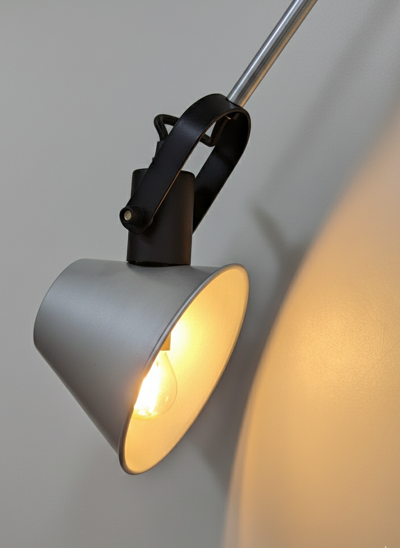 Industrial-style movable wall lamp with metal arm and clean geometry, mounted on a neutral wall.