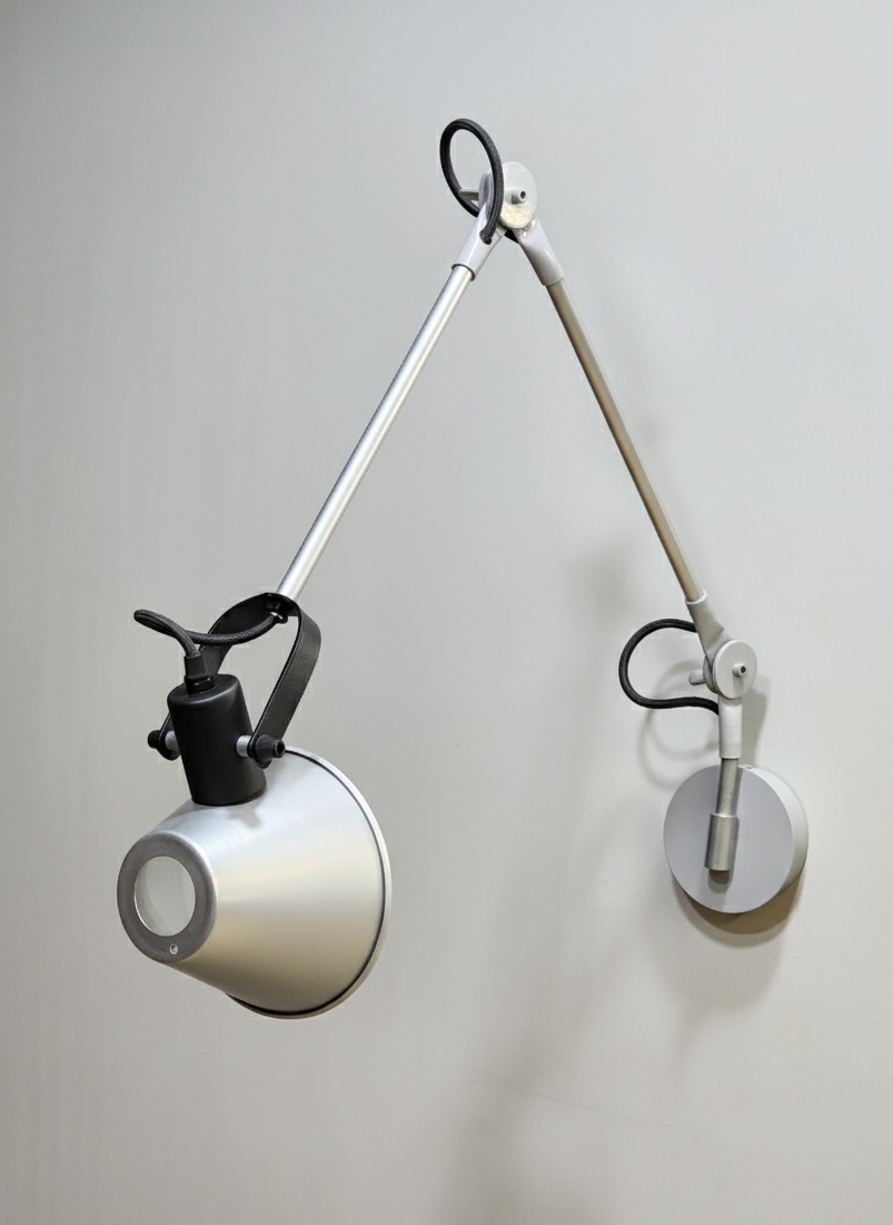 Minimal wall-mounted lamp with a movable arm, allowing precise control of light direction.