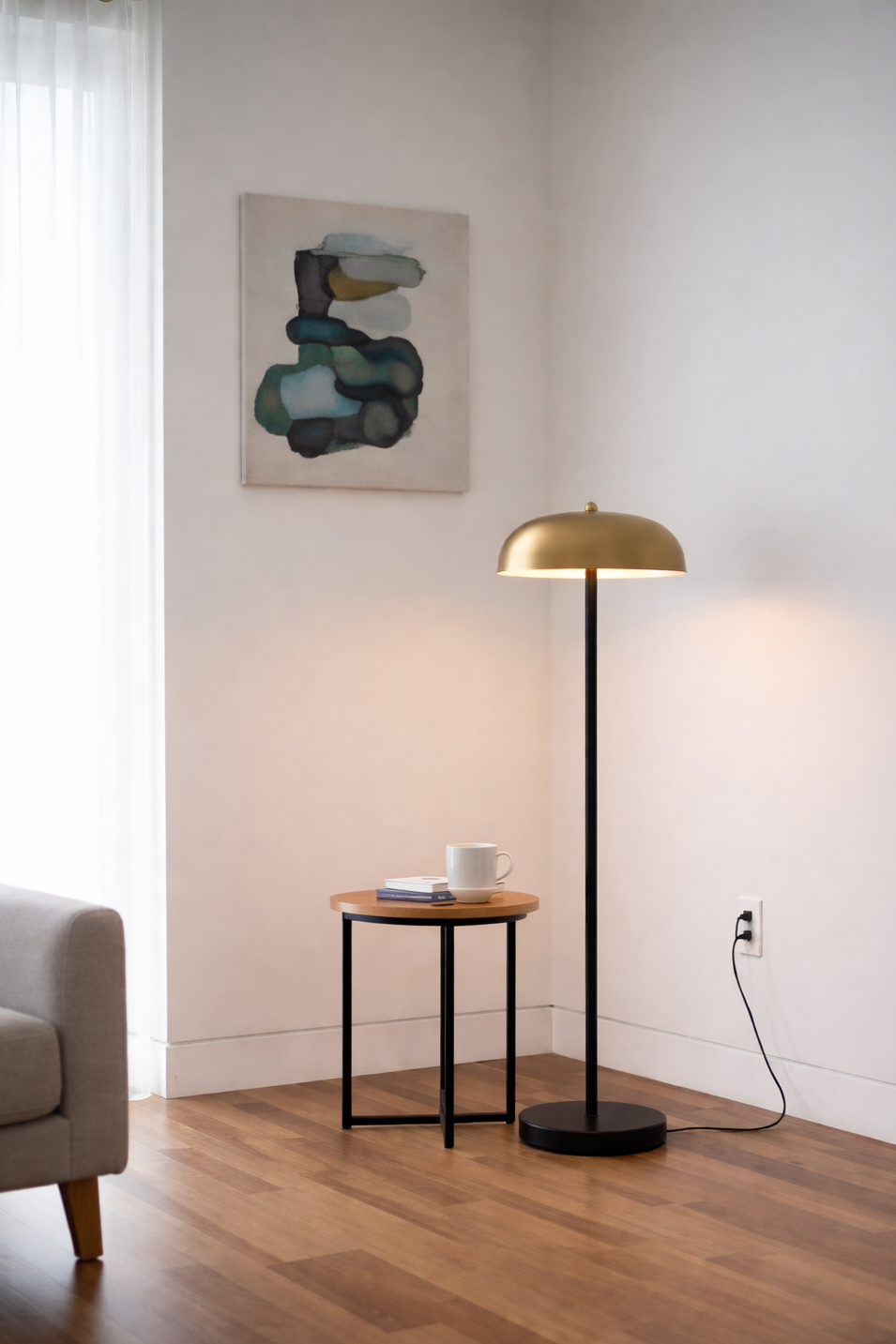 Modern living room with a gold floor lamp, side table, and abstract painting.