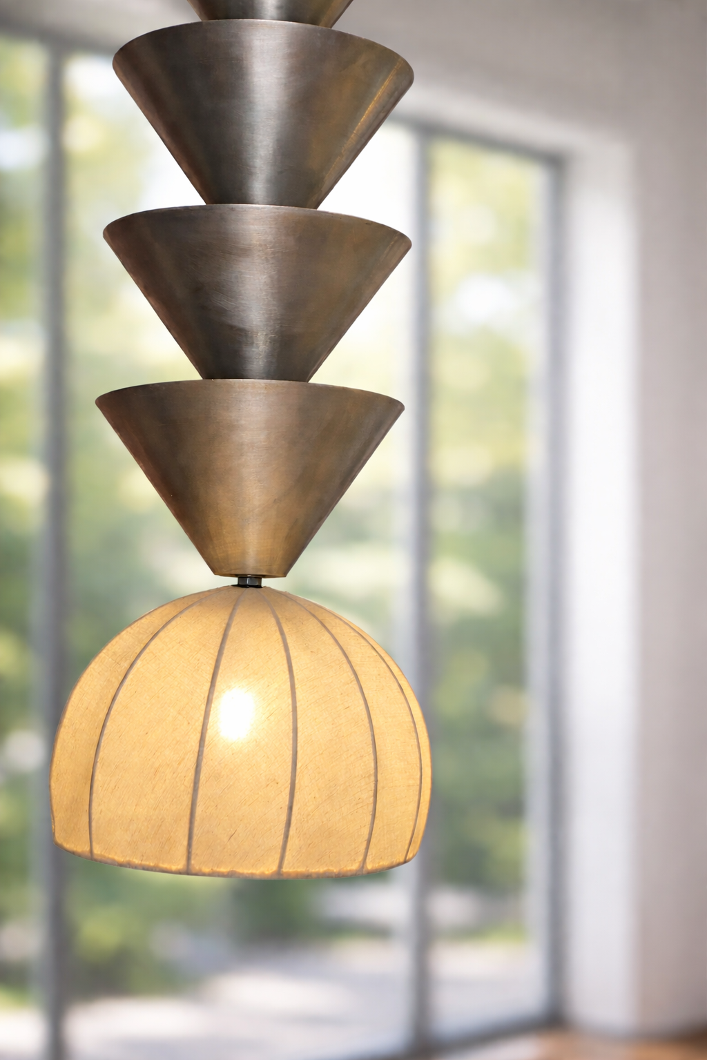 Modern pendant light with tiered design in a room with large windows.