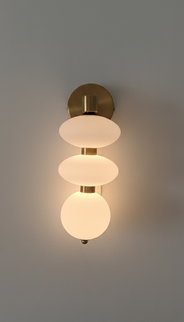 Modern wall light fixture with three glass shades on a gray background