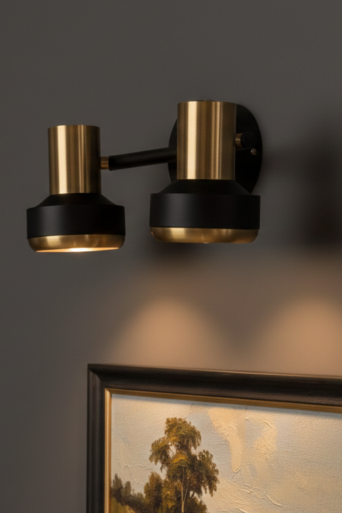 Modern wall sconce with gold and black finish on a dark wall.