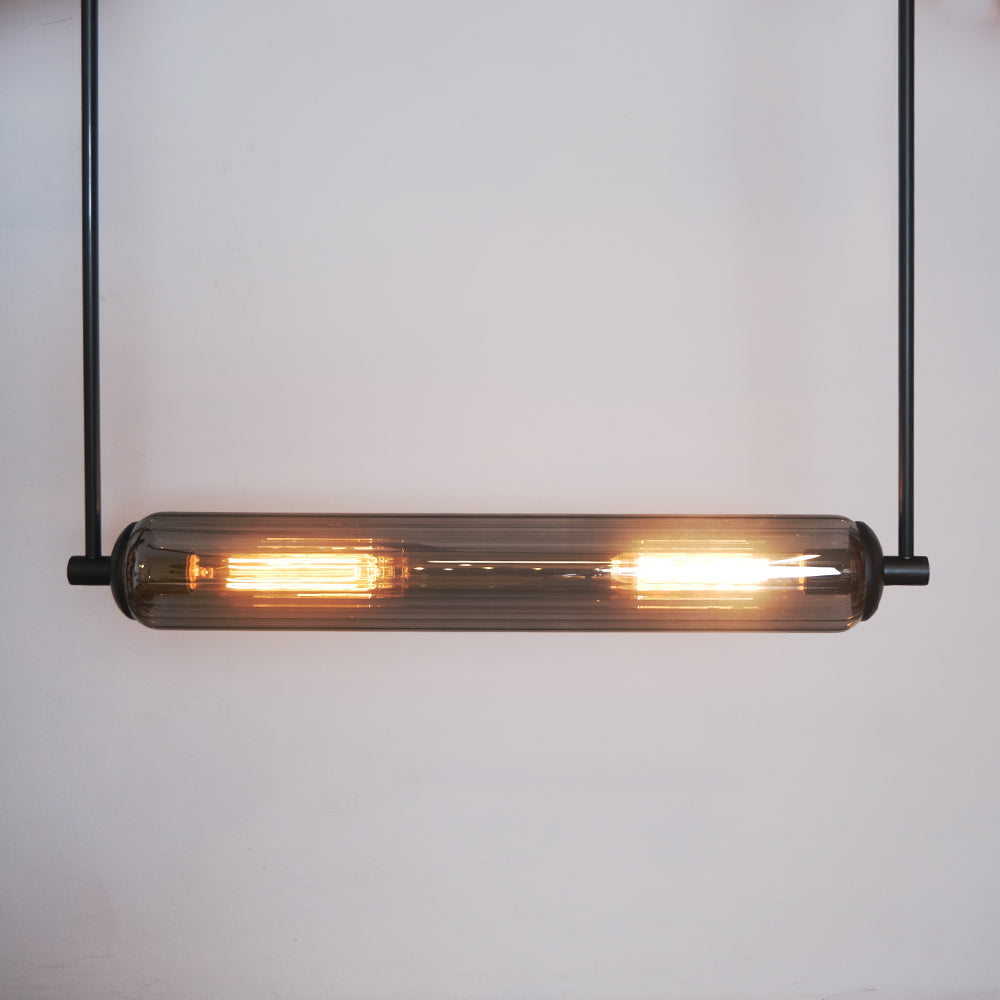 This modern lighting solution features an elongated glass tube encasing two glowing filament bulbs