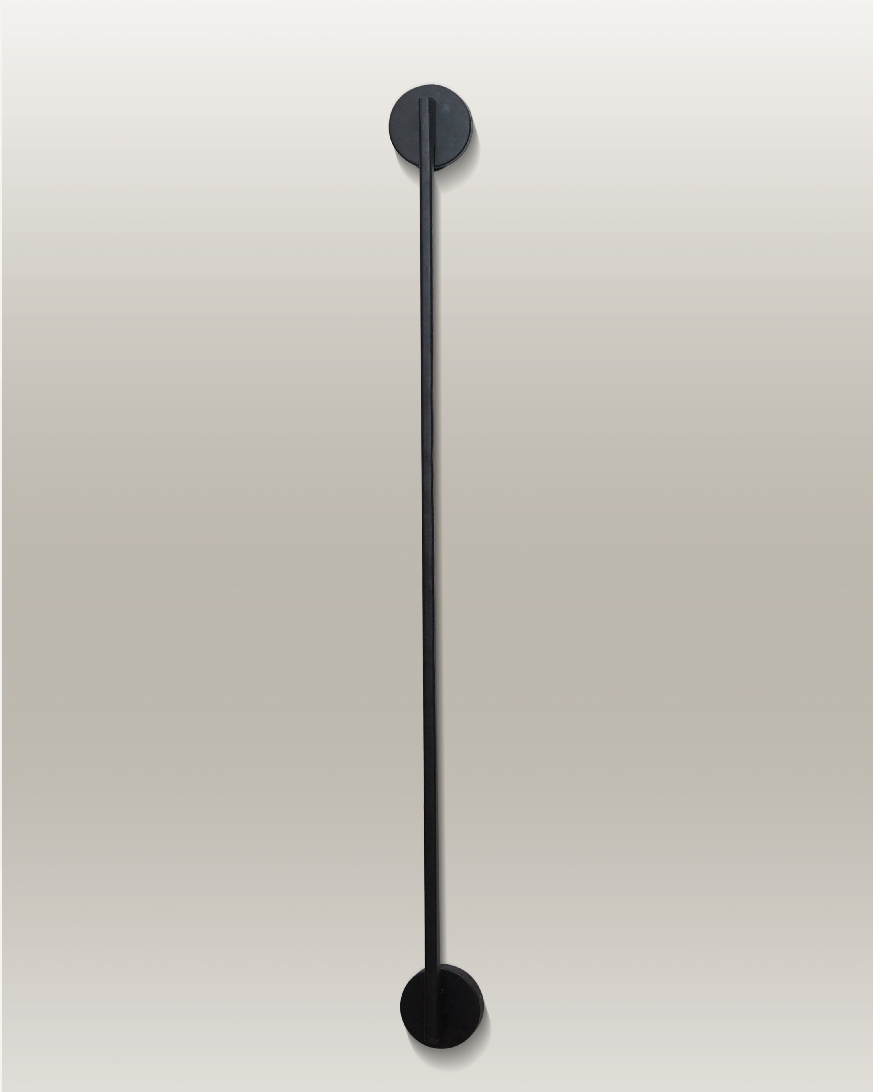 Vertical LED wall lamp with a sleek black finish, mounted with circular fixtures at the top and bottom ends.