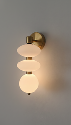 Wall-mounted light fixture with three glass shades on a gray wall.