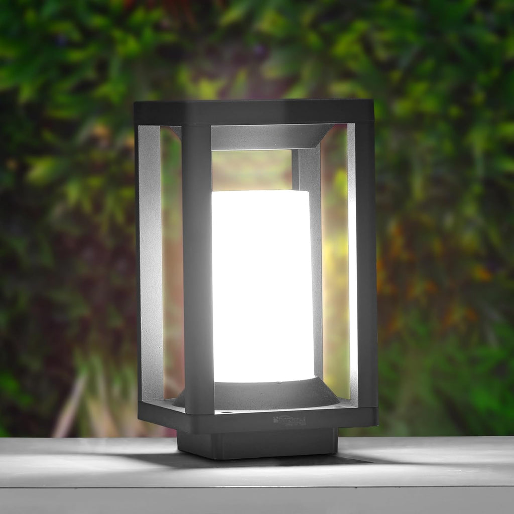 Black outdoor lamp with a white light on a blurred green background