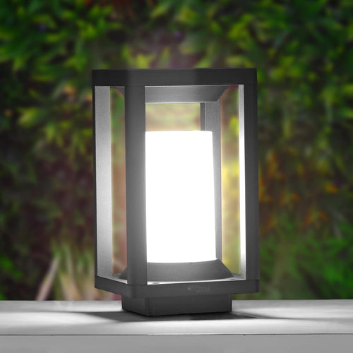 Black outdoor lamp with a white light on a blurred green background